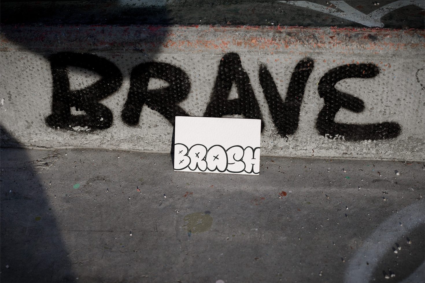 Urban stencil graffiti mockup with bold "BRAVE" text and editable "BRASH" card for font or logo display, street art, gritty texture.